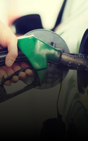 Mão abastecendo um carro com uma bomba de combustível verde em um posto de gasolina.