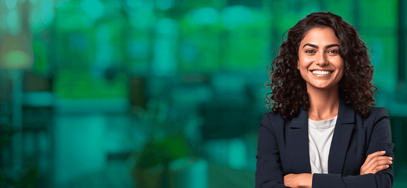 Mulher com terno de braços cruzados. Ela está sorrindo para a foto.