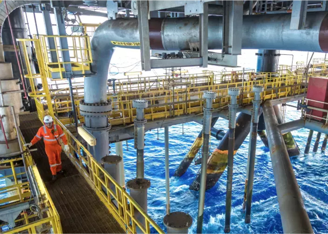 Oil platform at sea. There is an employee with safety PPE in one of the corridors.