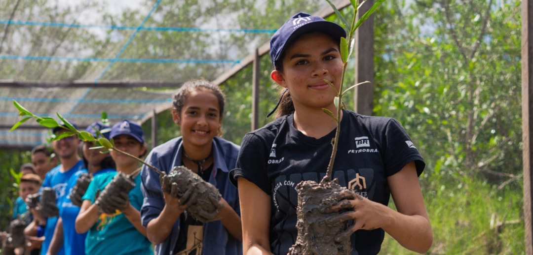 Crianças participantes do programa Mangues da Amazônia carregam mudas em viveiro do projeto.