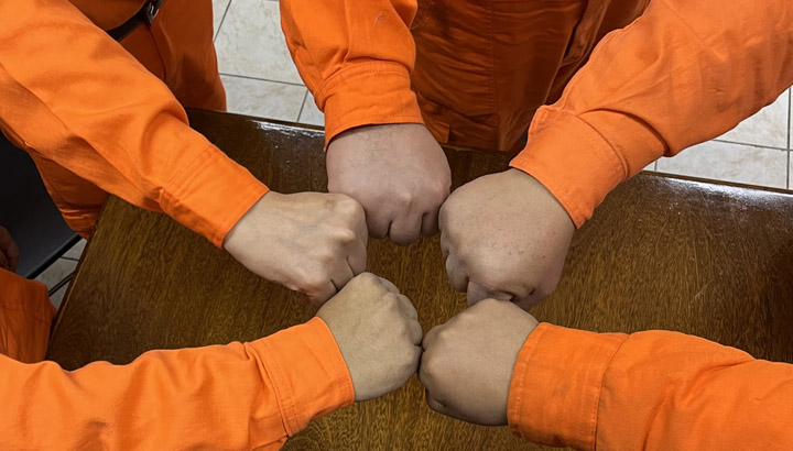 maos em punho e macacão laranja