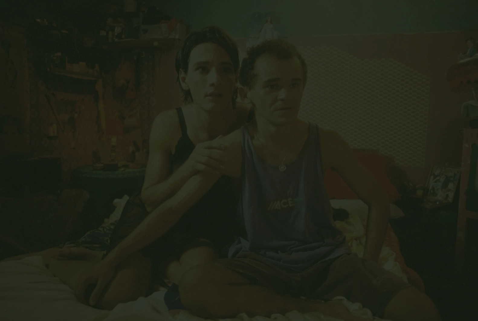 Lady Di e Sem Chance sentados em uma cama com expressões apreensivas, em cena do filme