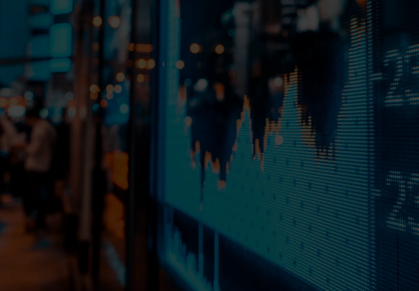 Nighttime photo of a street with a panel showing stock exchange information