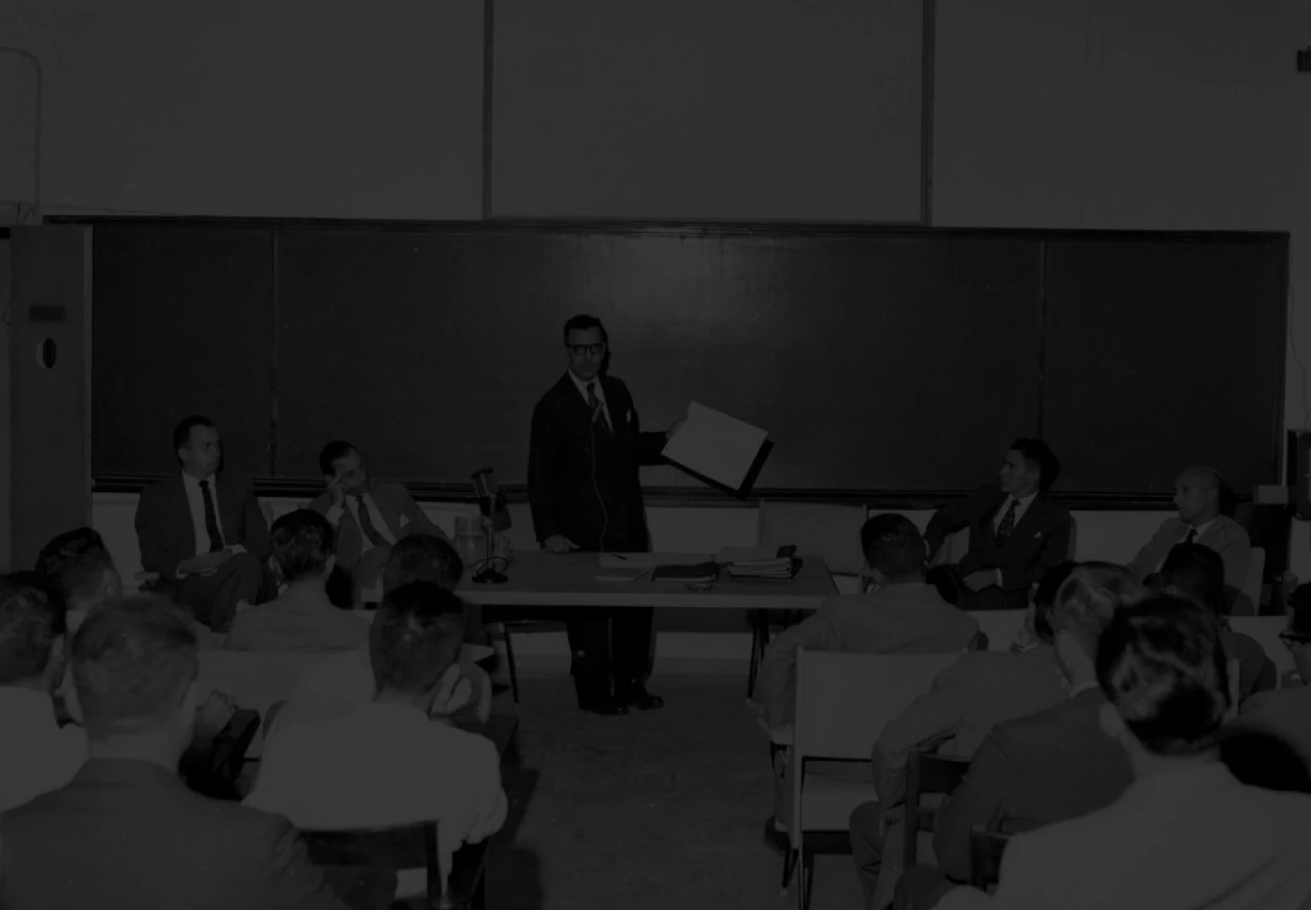 Black and white photo of a room at Cenap, full of people.