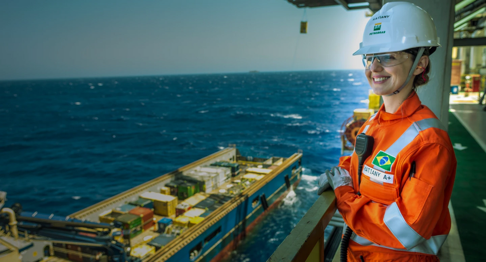 Funcionária com carreira na Petrobras em uma plataforma offshore, usando equipamento de proteção completo.