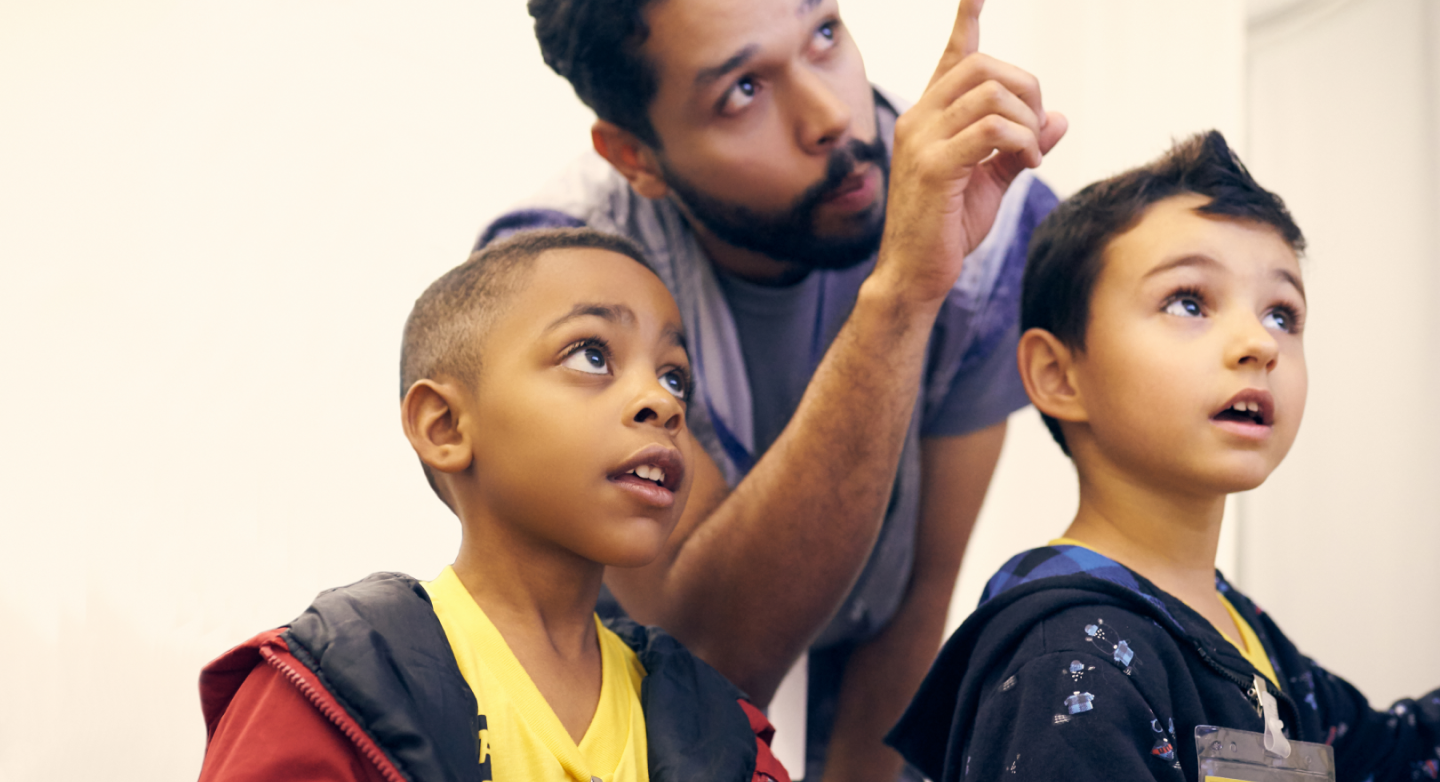 Adult pointing at something while talking to two children