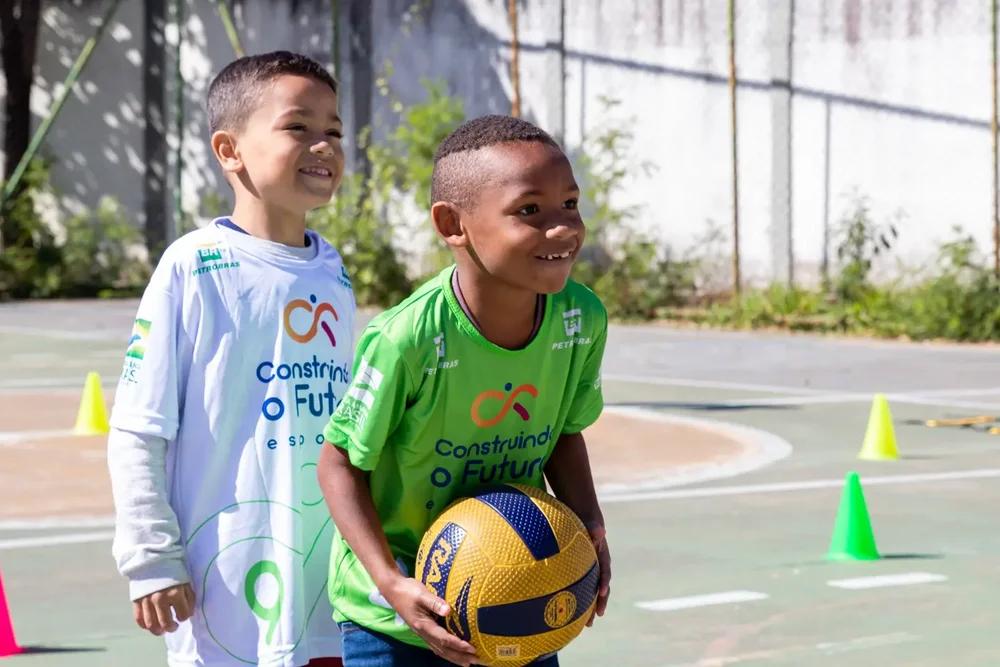 Child in uniform cutting paper in Petrobras' social and environmental program